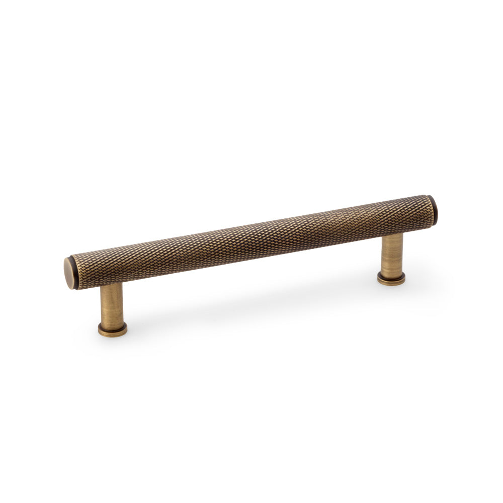 "Alexander & Wilks knurled T-bar cupboard pull handle in antique brass, 128mm centres, showing textured grip and vintage finish"