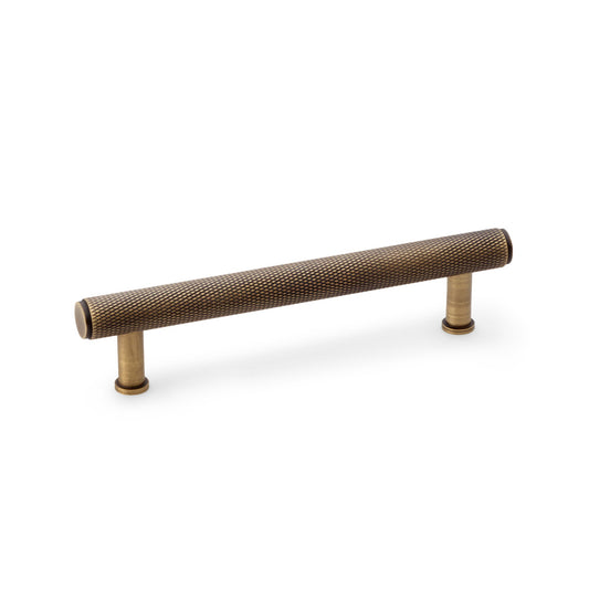 "Alexander & Wilks knurled T-bar cupboard pull handle in antique brass, 128mm centres, showing textured grip and vintage finish"