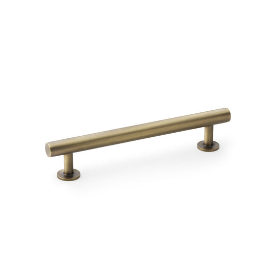 Antique brass T-Bar cabinet pull handle by Alexander & Wilks, 128mm centres, on wooden cabinet door.